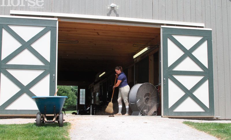 An equestrian cleaning the stable